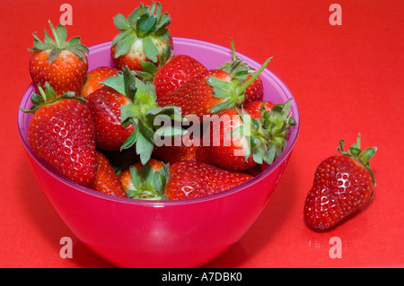 Fresh strawberries in a red and pink glass bowl on a red background Stockfoto