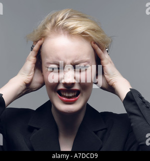 Jung betonte Geschäftsfrau mit Händen an den Kopf in der Verzweiflung Stockfoto