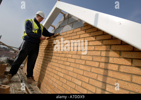 Azubi Maurer rundet eine Wand auf einer Neubausiedlung. Stockfoto