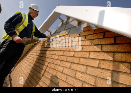 Azubi Maurer rundet eine Wand auf einer Neubausiedlung. Stockfoto