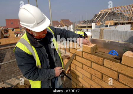 Erfahrene ältere Maurer eine Wohnsiedlung Ziegel Handauflegen Stockfoto