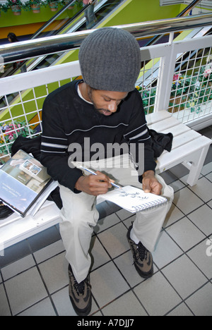 Junge schwarzer männliche Künstler zeichnet Bilder mit Bleistift und Papier Atlanta Georgia Stockfoto