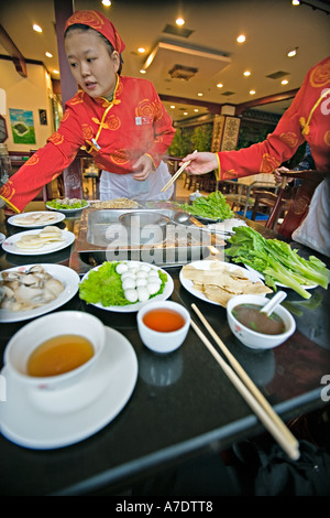 CHINA CHONGQING Zutaten für Chongqing Hotpot traditionelles Gericht durch freundliche Bedienung serviert und am Tisch gekocht Stockfoto