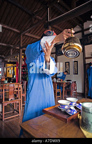 CHINA HANGZHOU Young Teetee Server gießt aus hohen verwenden Messing Teekanne Stockfoto