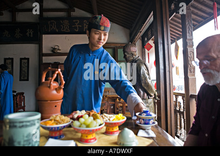 CHINA-HANGZHOU-Young Tee Server schüttet Tee für westliche Touristen Stockfoto