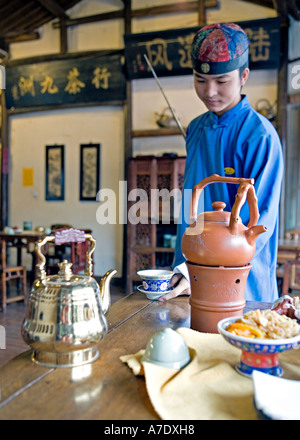 CHINA-HANGZHOU-Young Tee Server schüttet Tee hinter seinem Rücken mit antiken lange Tülle Teekanne Stockfoto