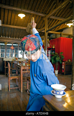 CHINA-HANGZHOU-Young Tee Server schüttet Tee hinter seinem Rücken mit antiken lange Tülle Teekanne Stockfoto