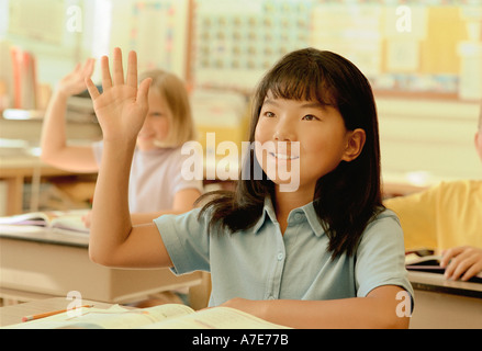 Eifrige Mädchen Hand in Klasse heben Stockfoto