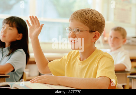 Eifrige junge hob Hand im Klassenzimmer Stockfoto