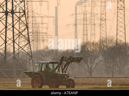 Ein Bauer seinen Traktor vor Hochspannung Pole und die Schornsteine der EON fahren Kohle-Kraftwerk Datteln Stockfoto