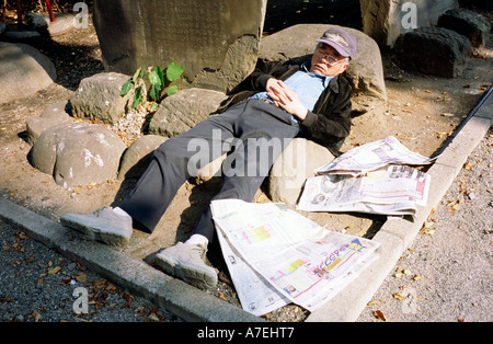 7. November 2004 - Mann schläft oben auf Felsen Anordnung innen Denkmal in Asakusa in der japanischen Hauptstadt Tokio. Stockfoto