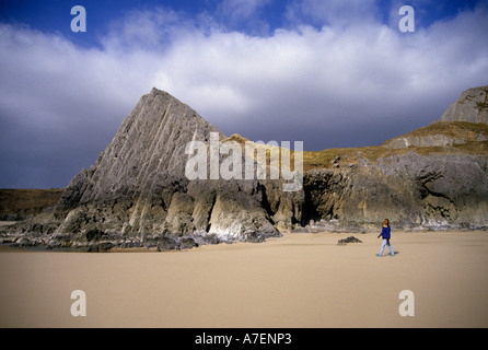Frau zu Fuß am leeren Strand von Three Cliffs Bay Gower Wales UK Stockfoto