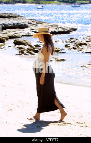 Eine gesunde junge schwangere Frau in einem Sarong Spaziergänge am Strand Stockfoto