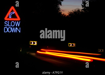 gefährliche Fahrt und die Beschleunigung in der Nacht unterwegs Haarnadelkurve. SLOW DOWN Zeichen Stockfoto