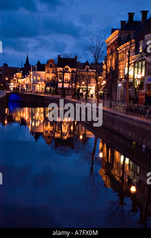 Nächtlicher Blick auf einen Kanal in Leeuwarden, Friesland, Holland, mit beleuchteten historischen Gebäuden und Reflexionen auf dem Wasser. Stockfoto