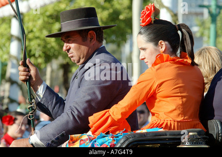 Wagen-Treiber mit einer Peitsche und ein Mädchen in einem Kleid orange Flamenco in Sevilla April Fair - Feria de Abril Stockfoto