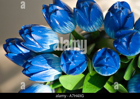 Nahaufnahme blauer künstlicher hölzerner Tulpen aus Holland, ein traditionelles holländisches Souvenir mit handgemalten Details und grünen Blättern. Stockfoto