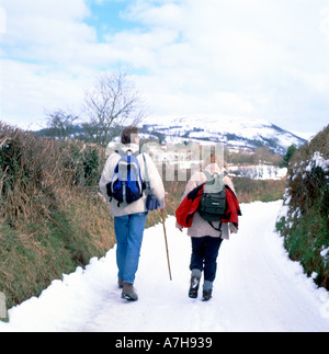 Spaziergänger gehen auf einer verschneiten Straße nach Llyn y Fan Im Brecon Beacons National Park in der Nähe von Llanddeusant in Carmarthenshire WALES GROSSBRITANNIEN KATHY DEWITT Stockfoto