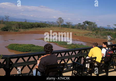 Touristen, die mit Blick auf das Wasserloch im Treetops Hotel, Aberdare Nationalpark, Kenia Stockfoto