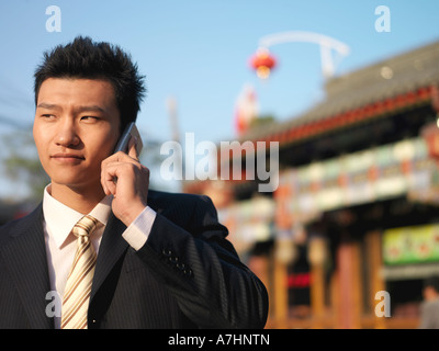 Ein junger chinesischer Geschäftsmann im Anzug auf seinem Handy zu sprechen Stockfoto