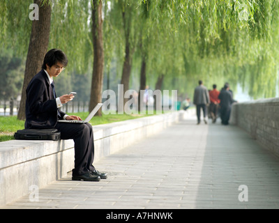 Junge chinesische Geschäftsmann im Anzug seine e-Mails auf seinem laptop Stockfoto