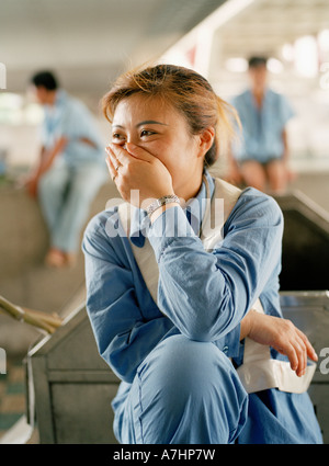 Eine chinesische Straße Reiniger nimmt eine Pause und bedeckt ihr Gesicht. Stockfoto