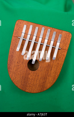 Hölzernes Kalimba-Musikinstrument mit sieben Metallzinken auf grünem Hintergrund. Traditionelles afrikanisches Daumenklavier. Stockfoto