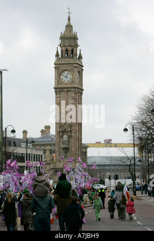 Parade-Goers wehenden bunte lila Bändern gehen Sie die Hauptstraße gegenüber dem Albert Memorial Clock und Harland und Wolff Stockfoto