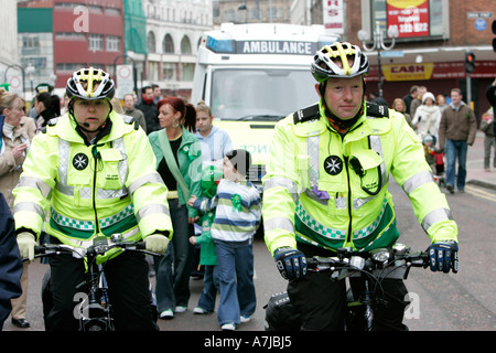 Zwei St John Ambulance Fahrrad Personal im Dienst mit Krankenwagen hinter Folgen der St. Patricks Day Stockfoto