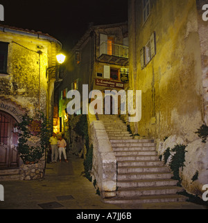 Mitte im Alter von Mann und Frau in engen Straße mit helle Lampe Overhead bewundern, Restaurant in der Nacht in Eze Sur Mer Südfrankreich Stockfoto