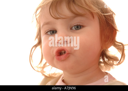 Porträt eines jungen Kindes auf weißem Hintergrund. Lockigen blonden, blauäugigen Mädchen mit gespitzten Lippen, als sie spricht. Baby Zähne sichtbar sind. Runde Wangen. Stockfoto