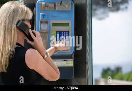 FRAU MIT ÖFFENTLICHES TELEFON IM AUSLAND Stockfoto