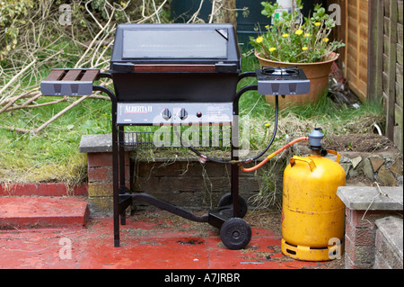 Gas Grill und gelb Butan Gaskartusche im Garten Stockfoto