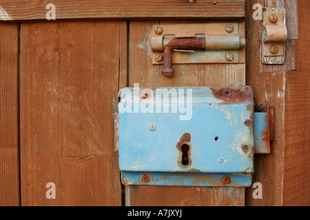 Altes blau lackiertes Schloss und rostiger Bolzen an einem hölzernen Gartentor. Stockfoto