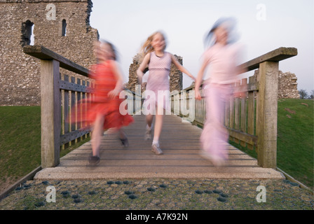 Drei junge Mädchen quer über eine Fußgängerbrücke Ogmore Schloss, South Wales. Die Mädchen sind unscharf, um Bewegung zu betonen. Stockfoto