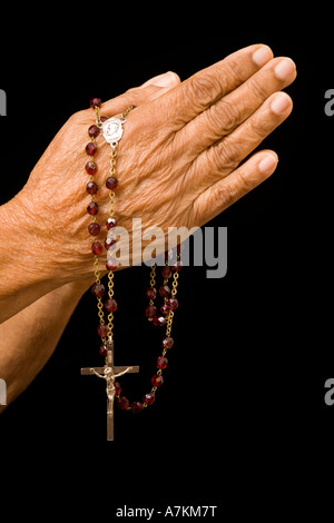 Eine alte asiatische Frau hält ihre Hände im Gebet mit einem Rosenkranz Stockfoto