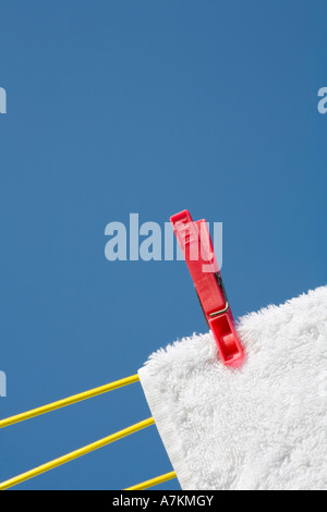 Kleidung pin auf ein weißes Handtuch und Wäscheleine vor blauem Himmel Stockfoto