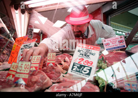 Ein Metzger ordnet seine Anzeige von Fleisch in das Fenster seines Ladens in Birmingham UK Stockfoto