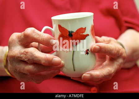 Nahaufnahme von einem älteren Damen arthritischen Händen hält eine Tasse Stockfoto