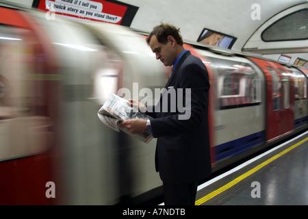 Stadt Gent Zeitungslektüre auf der Londoner U-Bahn Station mit Zug nähert sich England-Großbritannien Stockfoto