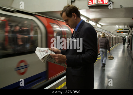 Stadt Gent Zeitungslektüre auf der Londoner U-Bahn Station mit Zug nähert sich England-Großbritannien Stockfoto