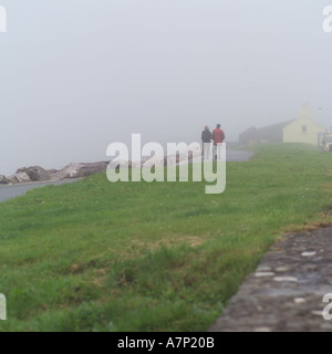 Menschen zu Fuß entlang der Küstenlinie in Nebel Irland Stockfoto
