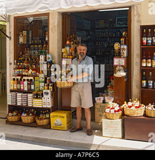 Besitzer des lokalen Spirituosen-Shop schaut in die Kamera im hellen frühen Morgen Sonnenschein in der schmalen Straße Corfu Stadt griechische Inseln Stockfoto