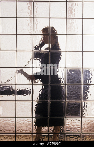 Business-Frau am Telefon hinter Glas Blockwand Stockfoto
