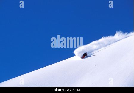 Extremer Snowboarder Mike Basich erstellen Spray von Schnee herab einen klaren Hang an einem sonnigen Tag in St. Moritz Schweiz Stockfoto