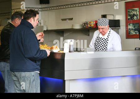 Man serviert Fish &amp; Chips in einem Meer-Fast-Food-Geschäft. Stockfoto