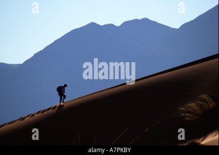 Ein Wanderer klettert auf den Grat einer Sanddüne in der Wüste Namib Namibrand Nature Reserve Namibia Stockfoto