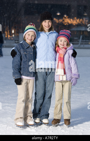 Drei Mädchen mit Schlittschuhen im Freien im Winter lächelnd Stockfoto