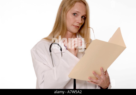 Durchdachte kaukasische Ärztin, die Patientennotizen auf der medizinischen Akte, USA überprüft. Stockfoto