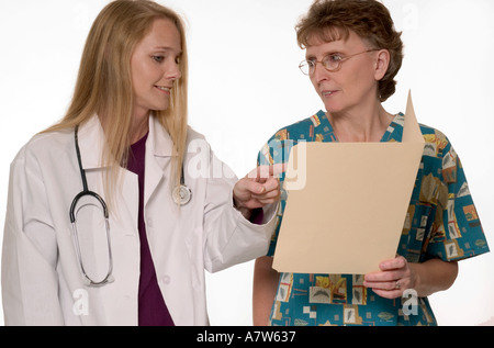 Kaukasische Allgemeinärztin diskutiert Patientenakte mit Krankenschwester in der Arztpraxis, USA. Stockfoto